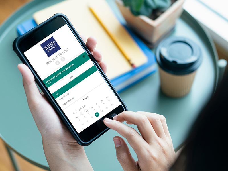 Dame med iphone som viser bookingkalender fra Thon Eiendom