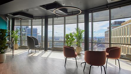 Bildet viser kontorfellesskapet Thon Flex i Stenersgata 2. En sittegruppe med tre røde stoler står i forkant av store vindusflater. Flott utsikt over Jernbanetorget, midt i Oslo sentrum.