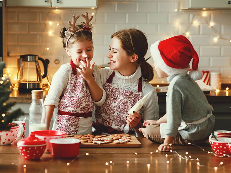 Bilde av en dame og to barn som baker med julestemning