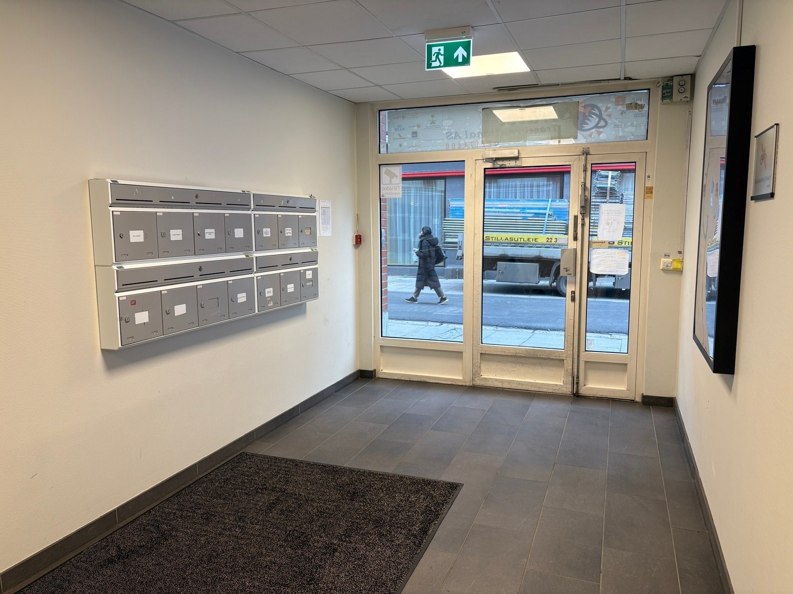 Inngangsparti med heis og infoskjerm for leietakeroversikt.